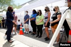 La vicepresidenta de EE. UU., Kamala Harris, a la izquierda, habla con trabajadores en una clínica emergente de vacunación COVID-19 afuera del Centro Internacional de Capacitación Carpenters en Las Vegas, Nevada, el 3 de julio de 2021.