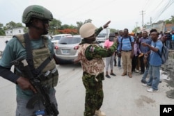 A Kenyan police officer takes photos of a group of Haitians welcoming the officers in Port-au-Prince, Haiti, on July 3, 2024.