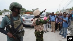 Seorang polisi Kenya tampak mengambil foto warga Haiti di di Port-au-Prince, pada 3 Juli 2024. (Foto: AP/Odelyn Joseph)