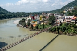 FILE - People walk on the Lakshman Jhula footbridge over the Ganges river in Rishikesh, India, Oct. 2, 2019.