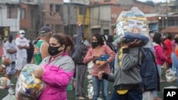 Los residentes se distancian socialmente en un campo de fútbol mientras están parados con bolsas de comida donadas por la ONG local "G10 Favelas", en el área de Capao Redondo de Sao Paulo, Brasil, el lunes 26 de abril de 2021.