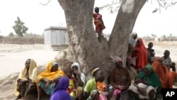 In this photo taken Feb. 18, 2019, Woman and Children displaced by Islamist extremist sits under a tree at Malkohi camp in Yola, Nigeria. 