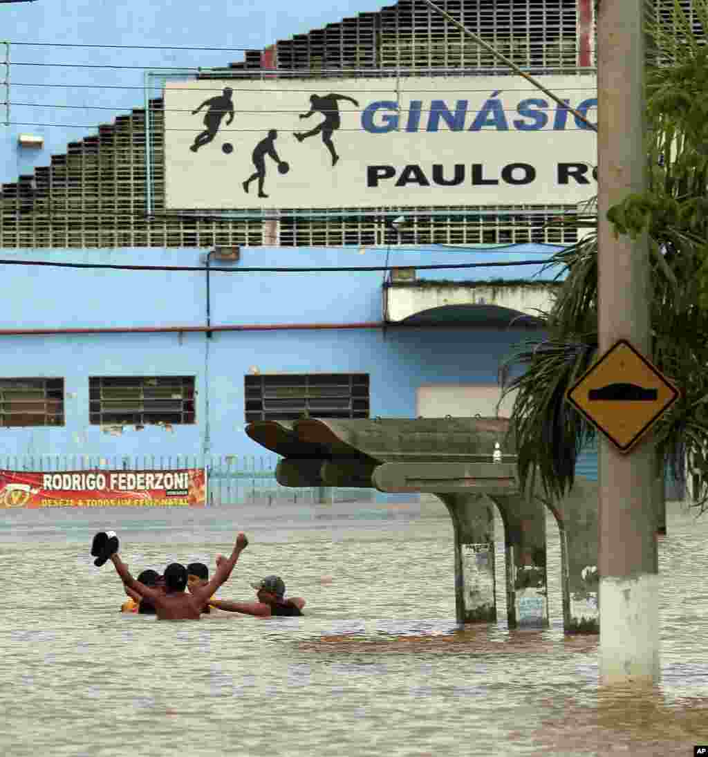 Jovens atravessam rua inundada em Franco da Rocha.