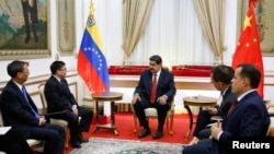 El presidente en disputa de Venezuela, reunido en la foto con funcionarios chinos, estaría obstaculizando los vuelos para repatriar a estadounidenses varados en ese país durante la pandemia.