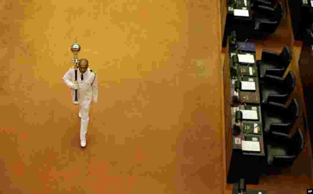 Sri Lanka's Sergeant-at-Arms Narendra Fernando carries the mace past empty seats of President Maithripala Sirisena and disputed Prime Minister Mahinda Rajapaksa at the beginning of the parliamentary session in Colombo.