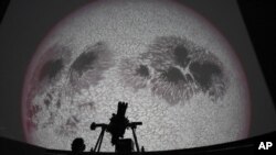 Researcher Ivannia Calvo, silhouetted against a solar satellite image, works inside the Solar Astronomical Observatory in San Jose, Costa Rica, Friday, April 30, 2021. Costa Rica approved a law creating a space agency on Feb. 18. (AP Photo/Carlos Gonzalez