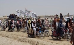 Supporters of the Taliban carry the Taliban's signature white flags in the Afghan-Pakistan border town of Chaman, Pakistan, July 14, 2021.