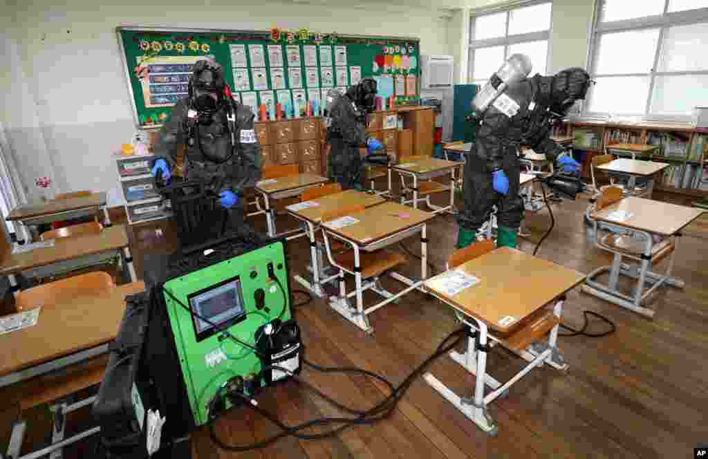 South Korean army soldiers spray disinfectant to help reduce the spread of the new coronavirus in a class at Cheondong elementary school in Daejeon.