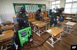 South Korean army soldiers spray disinfectant to help reduce the spread of the new coronavirus in a class at Cheondong elementary school in Daejeon.
