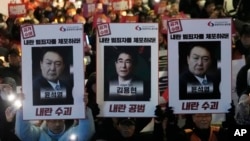 Protesters with images of South Korean President Yoon Suk Yeol and former South Korea Defense Minister Kim Yong Hyun, center, march to the presidential office in Seoul, South Korea, on Dec. 5, 2024. The signs read "Arrest the rebellion criminals."