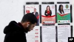 A man walks past campaign posters on Dec. 23, 2023, in Tunis. Tunisians will head to the polls on Sunday for the country's first local elections since voters approved a new constitution last year.