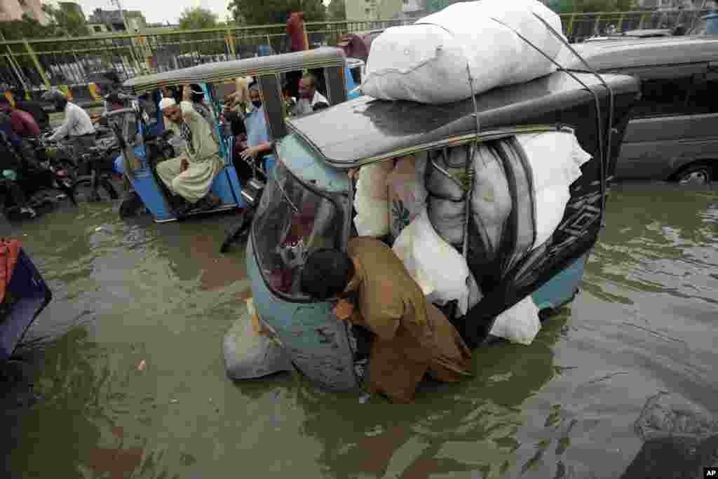 5Dereva asukuma tuktuk yake katika barabara ya Karachi, Pakistan iliyofurika na maji ya mvua kutonana na mvua za monsoon.