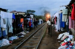 A man walks along a railway line as a commuter train approaches, amid the spread of the coronavirus disease (COVID-19), at the Kibera slums, in Nairobi, Kenya, July 6, 2020.