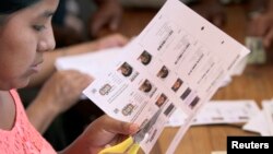 A member of a local election commission cuts voter registrations at a polling station in Villa 14 de Septiembre, in the Chapare region in Cochabamba, Oct. 12, 2014.