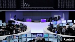 Traders at their desks at the Frankfurt stock exchange, Oct. 7, 2014. While stock market prices have risen, other investments have been subdued, according to the International Monetary Fund (IMF). 