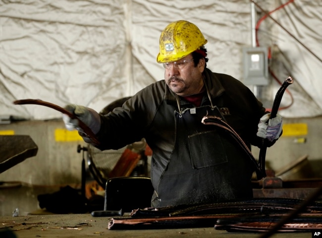 FILE - In this photo taken Friday, Dec. 1, 2017, Francisco Mendez strips insulation from copper wire at Midwest Scrap Management in Kansas City, Mo. (AP Photo/Charlie Riedel)