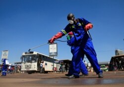 FILE - City health workers spray disinfectant at a bus terminus during a 21-day nationwide lockdown to limit the spread of coronavirus disease (COVID-19) in Harare, Zimbabwe, April 1, 2020.