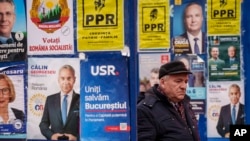 A man walks between panels displaying electoral posters ahead of the Nov. 24 presidential elections in Bucharest, Romania, Nov. 22, 2024.