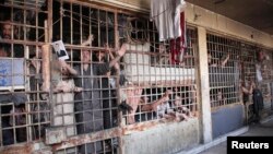 FILE - Inmates are seen behind bars in Aleppo's main prison, May 22, 2014. 