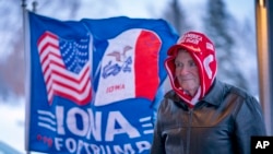 Seorang pria berdiri di samping bendera bertuliskan "Iowa untuk Trump" di luar Gudang Mesin di Urbandale, Iowa, 11 Januari 2024. (Foto: AP)