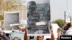 People hold signs during a protest march against Nigeria's President Muhammadu Buhari in Abuja, Feb. 6, 2017. 