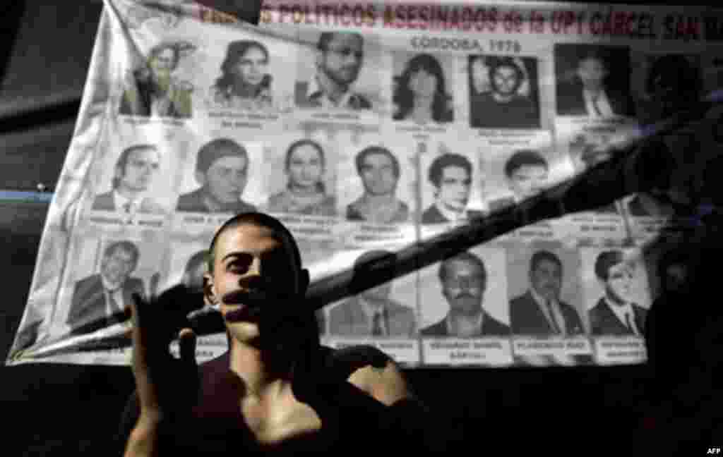 A man applauds in front a poster with images of victims killed during Argentina's dirty war as he listens the sentence for former dictator Jorge Videla in Cordoba, Argentina, Wednesday Dec. 22, 2010. Videla was sentenced to life in prison Wednesday for t