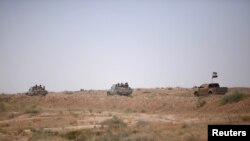 FILE - Popular Mobilization Forces (PMF) ride in military vehicles on the Iraqi border with Syria, Iraq, May 30, 2017.