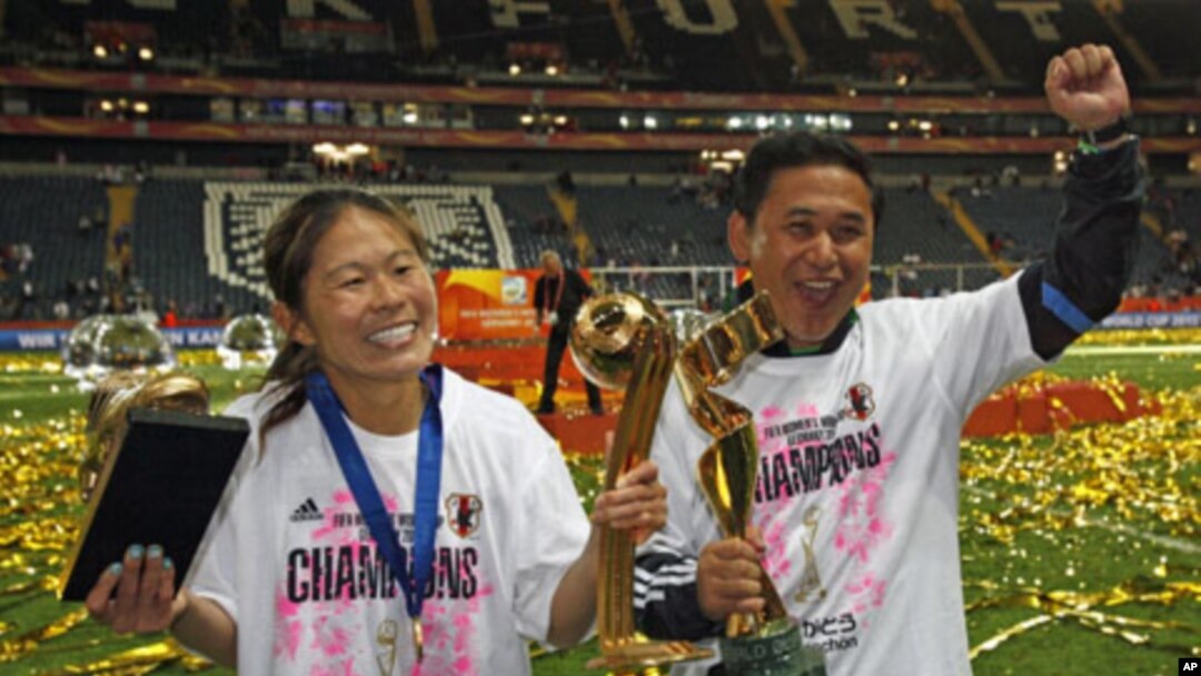 Japan's Homare Sawa (L) and head coach Norio Sasaki and pose with trophies after the end of their Women's World Cup final soccer match against the U.S. in Frankfurt, July 17, 2011