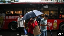 FILE - In this picture taken on October 18, 2023, passengers get off an electric bus in Shenzhen, China's southern Guangdong province. The damp passengers jostle their way onto the megacity's buses, part of a solution to coal-guzzling China's public transport network. 