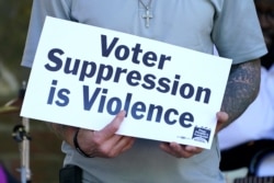 FILE - Benny Ivey, a former felon, holds a sign during an assembly in Jackson, Miss., April 19, 2021. Ivey was among speakers calling for a more simple way Mississippi to restore voting rights to people convicted of some felonies.