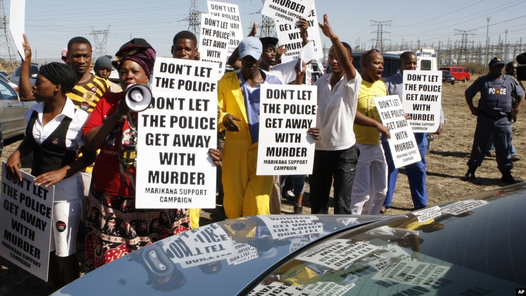 A group of protesters follow retired judge Ian Farlam and his team as they inspect the area where the bodies of mine workers were found after the shootings at Lonmin's platinum mine in Marikana near Rustenburg, South Africa, Oct. 1, 2012. 