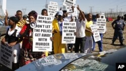 A group of protestors holds placards as a large crowd follows retired judge Ian Farlam and his team as they inspect the area where the bodies of mine workers were found after the shootings at Lonmin's platinum mine in Marikana near Rustenburg, South Africa, October 1, 2012. 