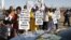 A group of protestors holds placards as a large crowd follows retired judge Ian Farlam and his team as they inspect the area where the bodies of mine workers were found after the shootings at Lonmin's platinum mine in Marikana near Rustenburg, South Africa, October 1, 2012.