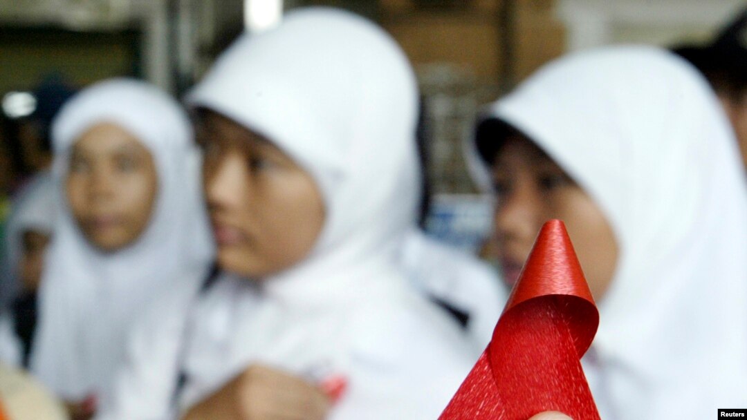 Seorang aktivis Indonesia membagikan pita merah kepada pelajar di stasiun kereta Jakarta dalam kampanye memperingati Hari AIDS Sedunia 1 Desember 2006. (Foto: Reuters)