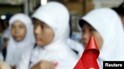 Seorang aktivis Indonesia membagikan pita merah kepada pelajar di stasiun kereta Jakarta dalam kampanye memperingati Hari AIDS Sedunia 1 Desember 2006. (Foto: Reuters)