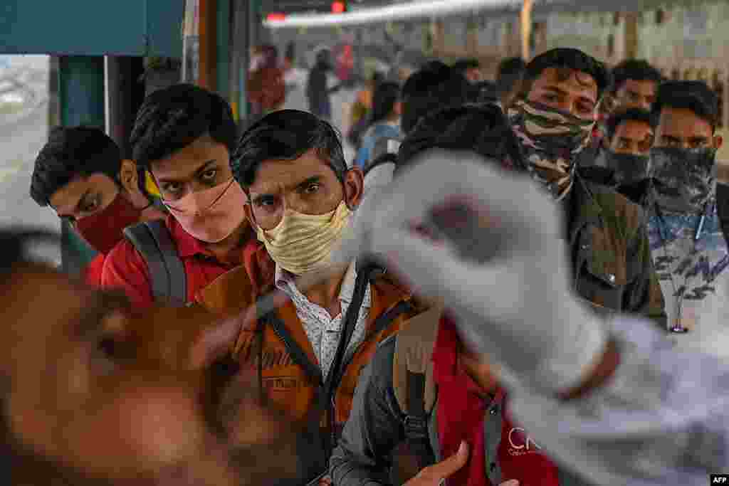 Passengers queue up as they watch a nasal swab sample being taken during a COVID-19 screening after arriving at a railway platform on a long-distance train, in Mumbai .