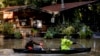 Kevin Ozorkiewicz, left, and neighbor John Phillips paddle a canoe at the flooded Mirabel RV Park & Campground after a major storm in Forestville, Calif., Sonoma County, Nov. 23, 2024. 