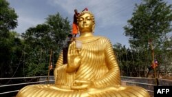 A Buddhist monk climbs atop a giant statue of Buddha to wash and decorate on the eve of Buddha Purnima, a holiday traditionally celebrated for Buddha&#39;s birthday also known as Vesak celebrations, in Bhopal, India.