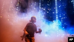 A protester stands in the midst of tear gas during confrontation with police in Hong Kong, Aug. 4, 2019. 