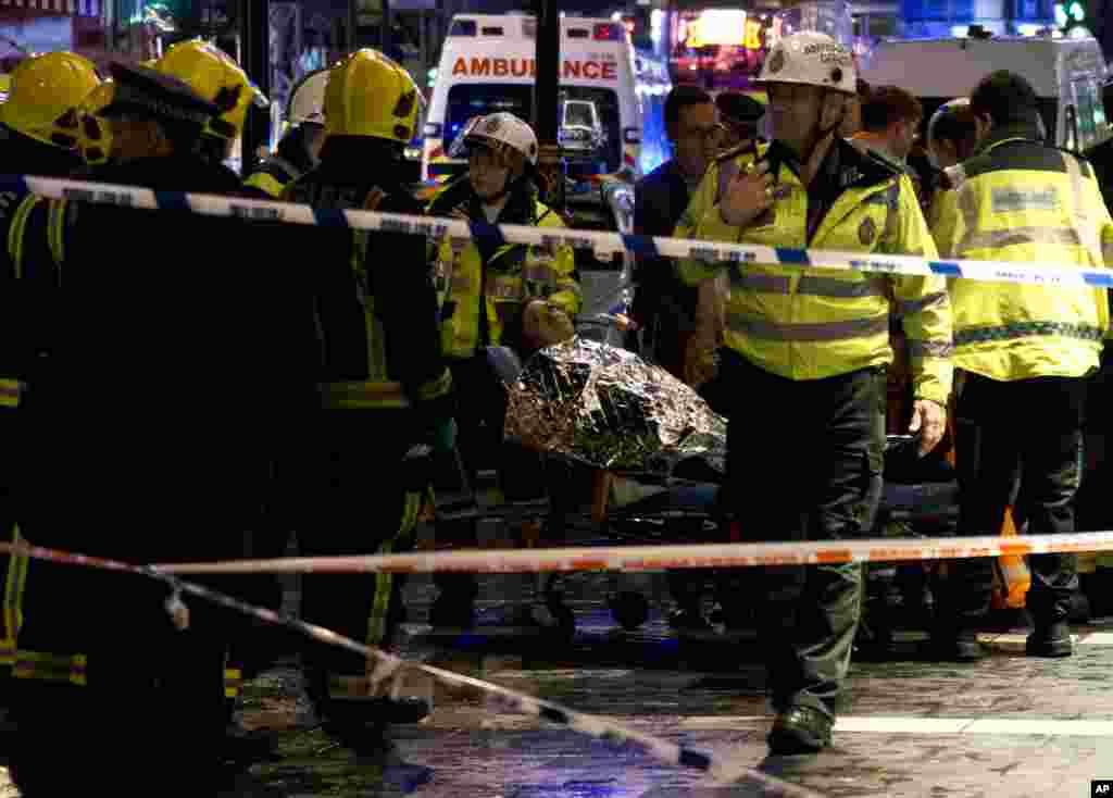 A woman lies on a stretcher surrounded by rescue workers, awaiting evacuation after part of the ceiling collapsed during a performance at the Apollo Theatre, Shaftesbury Avenue, London, Dec. 19, 2013.
