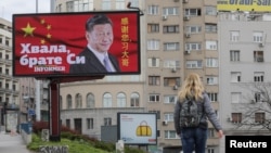FILE - A woman passes by a billboard depicting Chinese President Xi Jinping in Belgrade, Serbia, April 1, 2020. The text on the billboard reads "Thanks, brother Xi.”