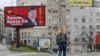 FILE - A woman passes by a billboard depicting Chinese President Xi Jinping in Belgrade, Serbia, April 1, 2020. The text on the billboard reads "Thanks, brother Xi.”