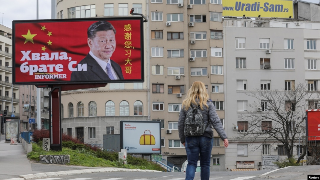 FILE - A woman passes by a billboard depicting Chinese President Xi Jinping in Belgrade, Serbia, April 1, 2020. The text on the billboard reads "Thanks, brother Xi.”