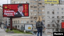 FILE - A woman passes by a billboard depicting Chinese President Xi Jinping in Belgrade, Serbia, April 1, 2020. The text on the billboard reads "Thanks, brother Xi.”