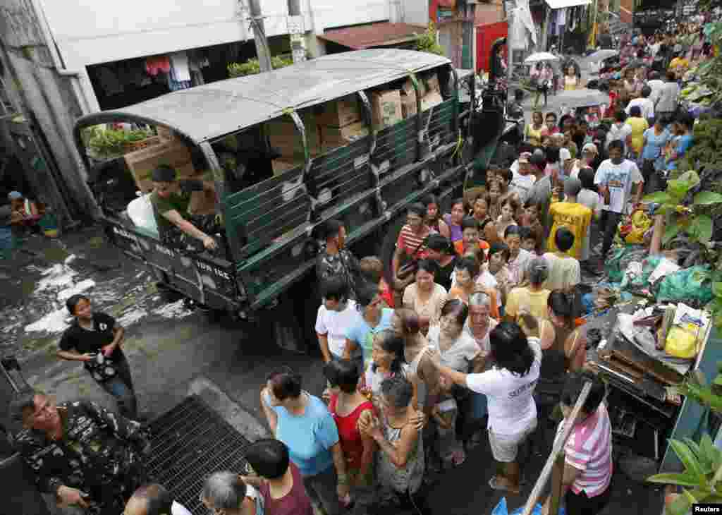 Residents queue for relief goods after their shanties were submerged by floodwaters brought by monsoon rains in Sta Mesa, metro Manila, August 13, 2012. 