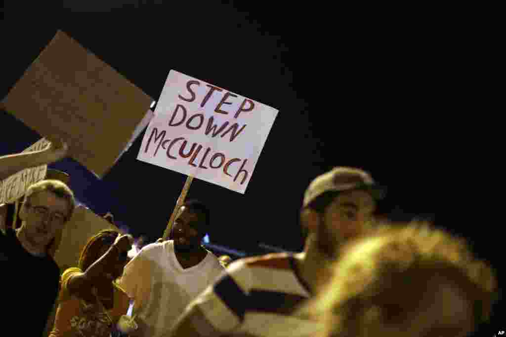Manifestantes marcham junto ao local onde Michael Brown foi morto em Ferguson, Missouri, Ago. 21, 2014.