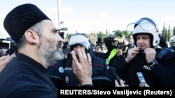 Montenegro, Podgorica, A Serbian Orthodox Church priest speaks with a riot policeman on a bridge near the parliament