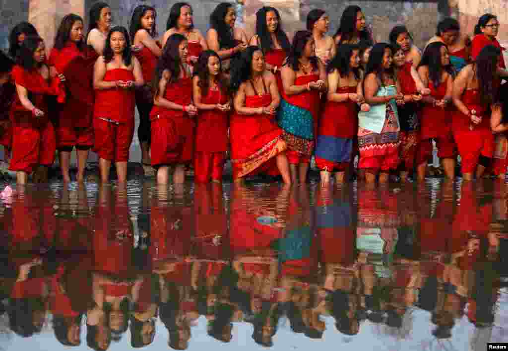 Devotees offer prayers as they stand on the bank of the Hanumante River during the final day of the month-long Swasthani Brata Katha festival in Bhaktapur, Nepal.