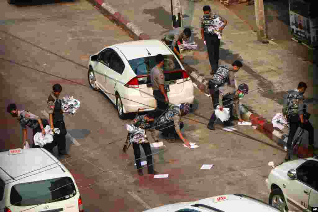 Police officers clear the road after demonstrators spread placards in Yangon, Myanmar, April 24, 2021.