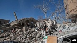 People inspect the wreckage of buildings that were damaged by Saudi-led coalition airstrikes, in Sanaa, Yemen, Tuesday, Jan. 18, 2022.